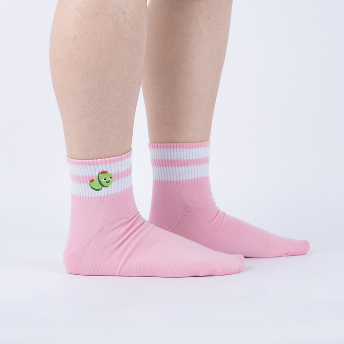 Lifestyle shot of person wearing pink ankle socks with olive embroidery and white stripes.