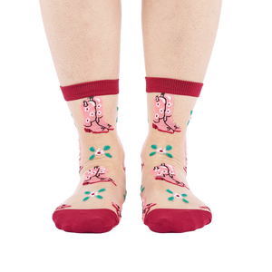 A person's legs and feet, wearing sheer pink cowboy boot socks, viewed from the front against a white background.