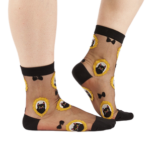 Person's lower legs and feet wearing the sheer black cat socks, standing on a white background.