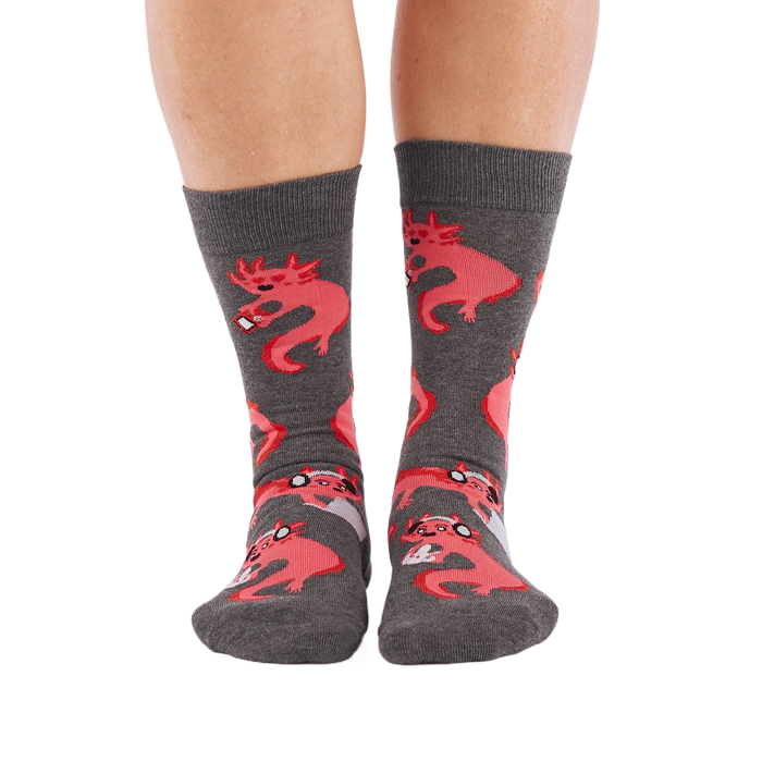 Full-length shot of a person's legs, viewed from the front, wearing grey axolotl gaming crew socks on a white background.