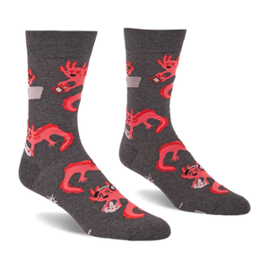 Pair of grey crew socks with a repeating pattern of coral pink axolotls holding game controllers and smartphones.