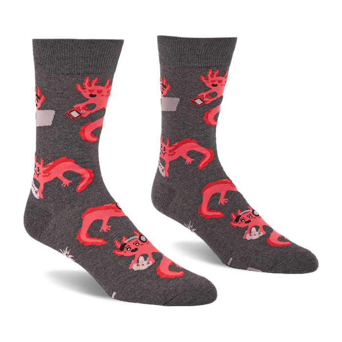 Pair of grey crew socks with a repeating pattern of coral pink axolotls holding game controllers and smartphones.