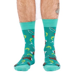 Front view of a person wearing teal fly fishing socks, showing leg hair and a partial tattoo on the right calf.