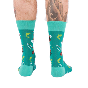 Back view of a person wearing teal fly fishing socks, showing leg hair and tattoos on both calves.
