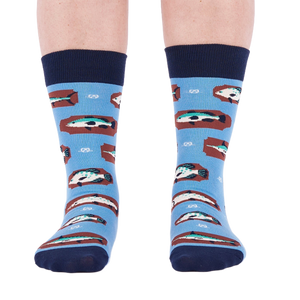 Person standing forward wearing light blue crew socks with fish and knot patterns on a white background.