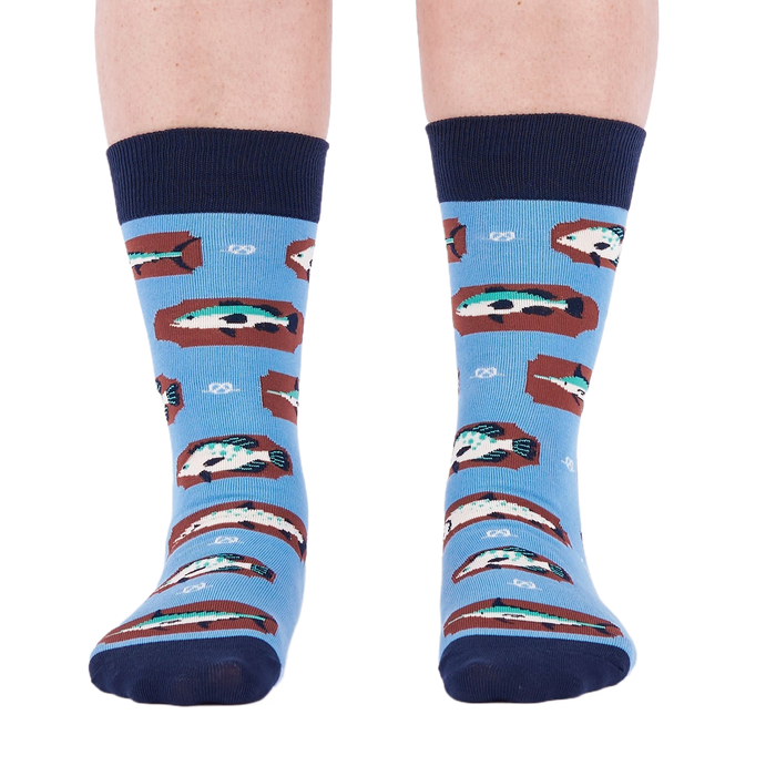 Person standing forward wearing light blue crew socks with fish and knot patterns on a white background.