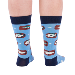 Person standing backward, showing the heels of light blue crew socks with fish and knot patterns on a white background.