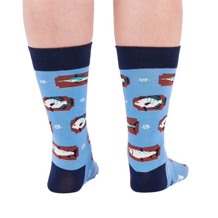 Person standing backward, showing the heels of light blue crew socks with fish and knot patterns on a white background.