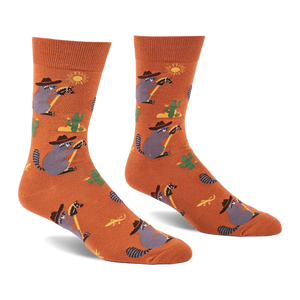 A pair of burnt orange crew socks with cartoon raccoons in cowboy hats lassoing, green cacti, yellow suns, and lizards.