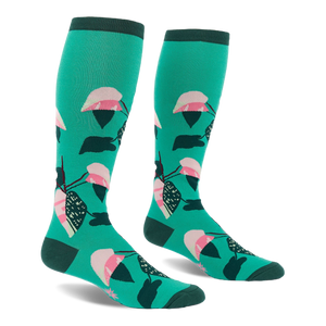Pair of knee-high teal socks with a repeating philodendron leaf pattern in pink, white, dark green, and black. Dark green cuffs, heels, and toes.