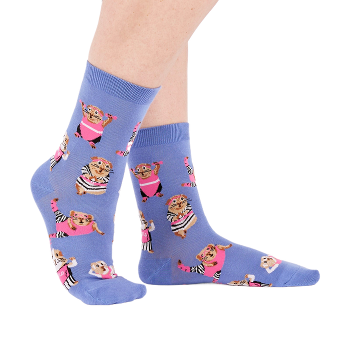 Person's feet wearing periwinkle crew socks with a guinea pig workout pattern, viewed from the side on white.