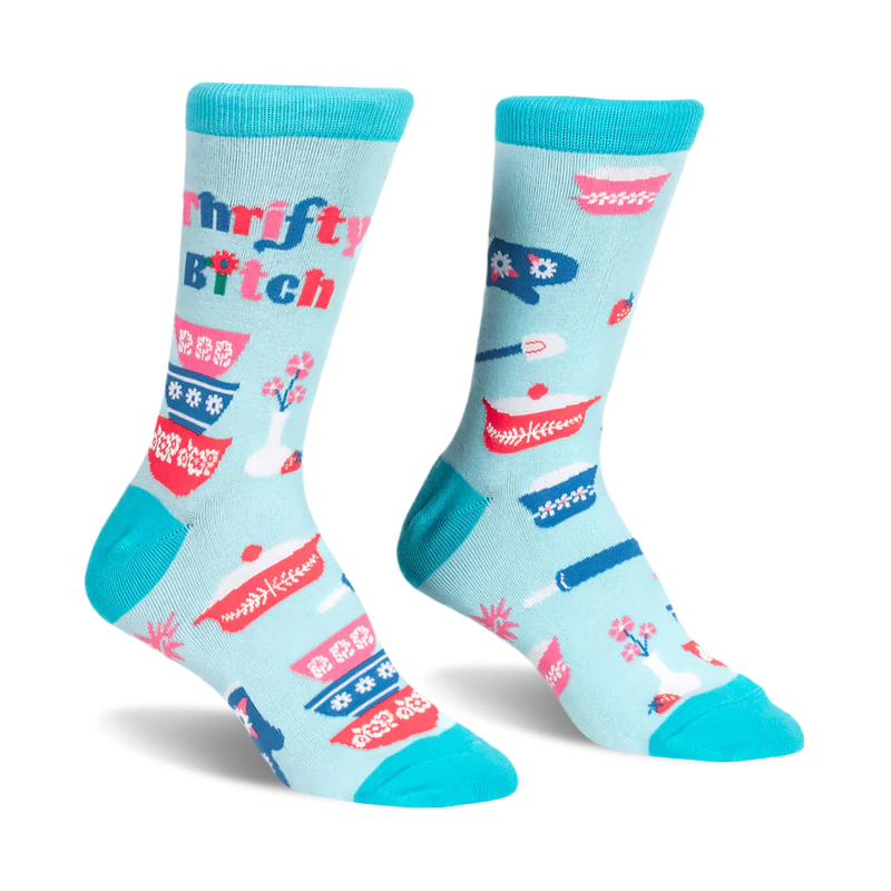 Light blue crew socks with teal trim featuring retro patterned mixing bowls, baking tools, and Thrifty B*tch text.