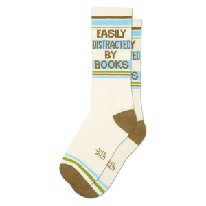 Pair of cream crew socks with 'Easily Distracted By Books' in green text, horizontal brown, blue, and green stripes.