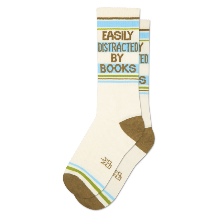 Pair of cream crew socks with 'Easily Distracted By Books' in green text, horizontal brown, blue, and green stripes.