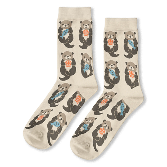 Cream crew socks featuring a pattern of floating brown sea otters holding light blue fish and bright orange shells.