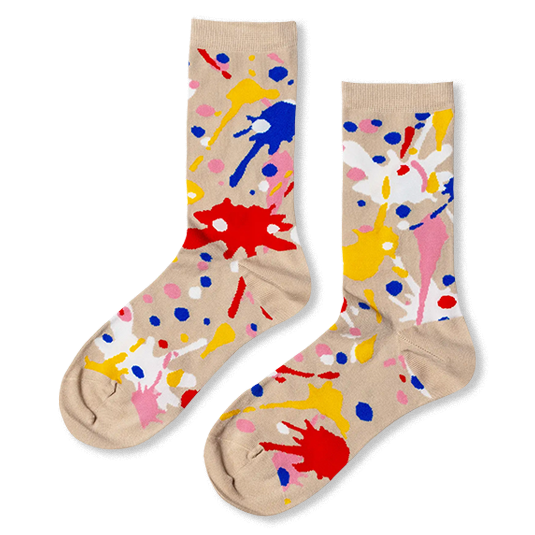 Beige crew socks featuring a chaotic pattern of bright red, blue, yellow, pink, and white paint splatters and dots.