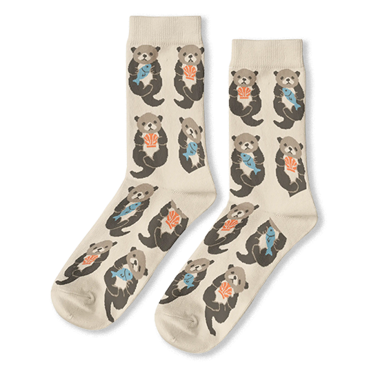 Cream crew socks featuring a pattern of brown sea otters floating on their backs holding blue fish and orange shells.
