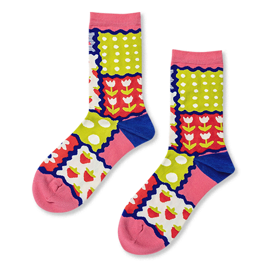 Crew socks with a colorful patchwork design of strawberries, tulips, polka dots and stripes separated by wavy blue borders.