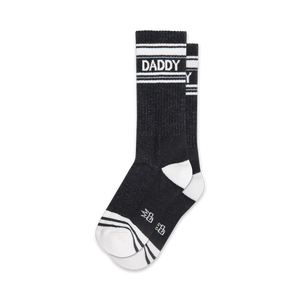 Pair of black crew socks with white stripes and 'DADDY' text.  Sporty and playful design.