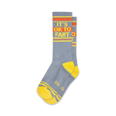 Pair of gray crew socks with yellow and orange stripes and the phrase 'It's Ok to Fart'.