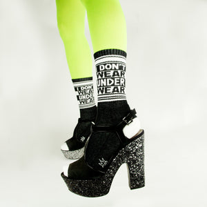Lifestyle shot: Model wearing neon green tights and black platform shoes with the 'I Don't Wear Underwear' socks.