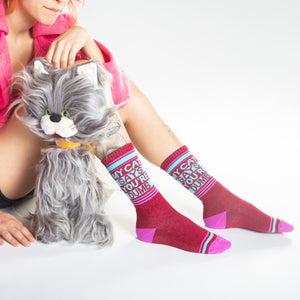 Another lifestyle shot of a model wearing the socks and sitting with a gray cat toy.