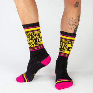 Lifestyle photo showing a person wearing the black 'Everything Hurts And I'm Dying' crew socks.