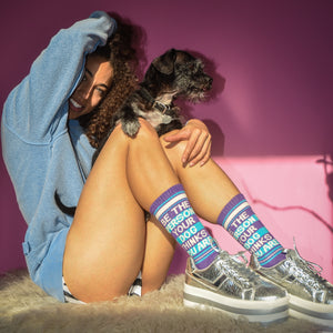 Lifestyle photo of a woman wearing the socks with her dog.  She's smiling and looks happy.
