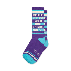 Pair of purple and teal crew socks with the text 'Be The Person Your Dog Thinks You Are' written vertically.
