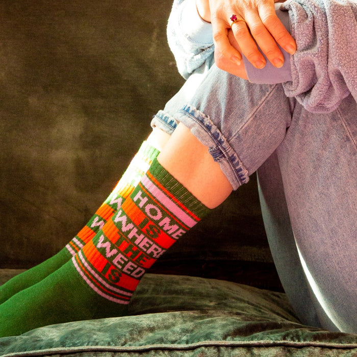 A person is sitting on a green couch wearing blue jeans and green socks with the words 