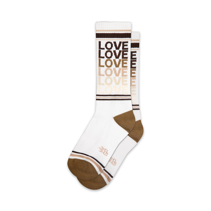 Lifestyle shot of model wearing rainbow 'Love' socks with rainbow platform sandals against a pink background.