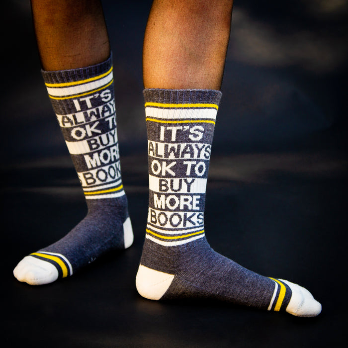 Lifestyle photo showcasing the 'It's Always Ok To Buy More Books' socks on a person's feet.