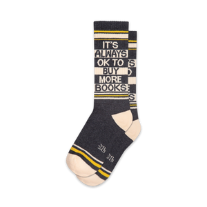 Pair of crew socks in dark grey, white, and yellow.  The socks feature the text 'It's Always Ok To Buy More Books!' in a striped design.