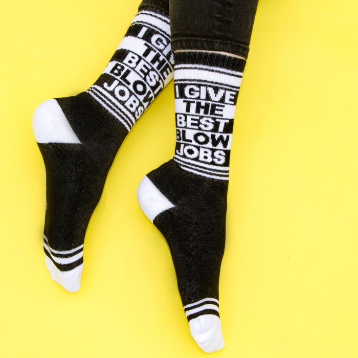 Lifestyle shot: A person's legs wearing the 'I Give The Best Blow Jobs' socks against a yellow background.