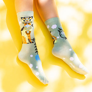 Flat lay of Cat & Clouds socks on a yellow background.