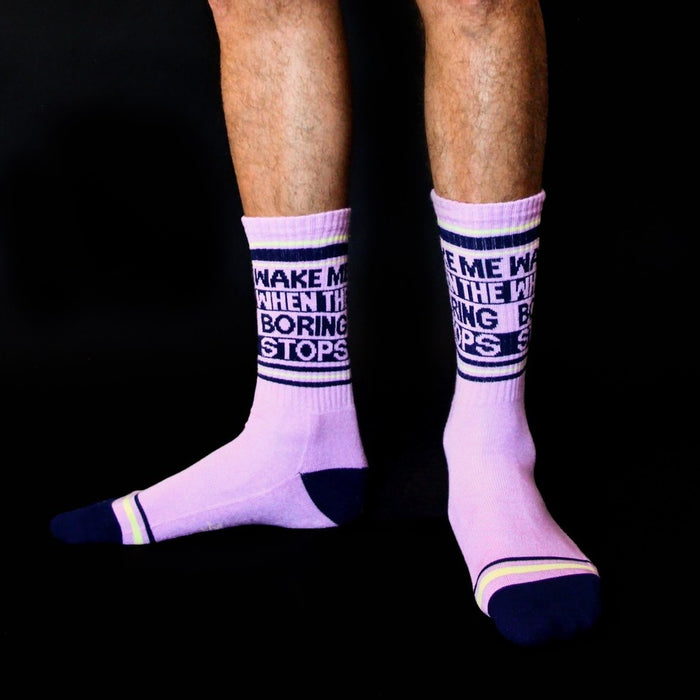 Lifestyle shot of a person wearing the 'Wake Me When the Boring Stops' socks. The socks are lavender with navy and yellow details.