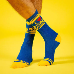 A pair of blue socks with a yellow toe, heel, and two yellow stripes around the top. The word PUZZLE is written in red on the front of the socks.