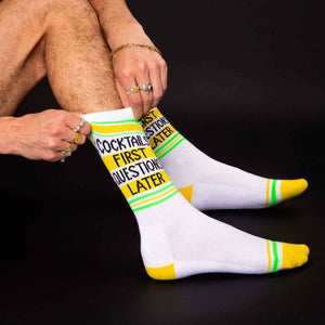 Close-up shot of a man putting on the 'Cocktails First Questions Later' socks.