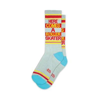 Pair of light gray crew socks with red and yellow stripes and the text 'Here Comes A Roller Skater'.  Features a teal colored heel and toe.