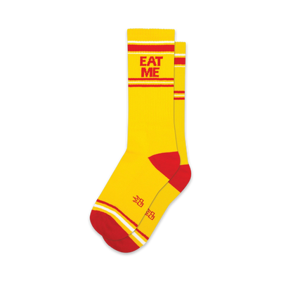 A pair of yellow crew socks with red and white stripes and the words 'EAT ME' in red.  Small logo on the sole.
