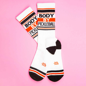 Flat lay of a pair of 'Body By Pickleball' socks on a pink background.