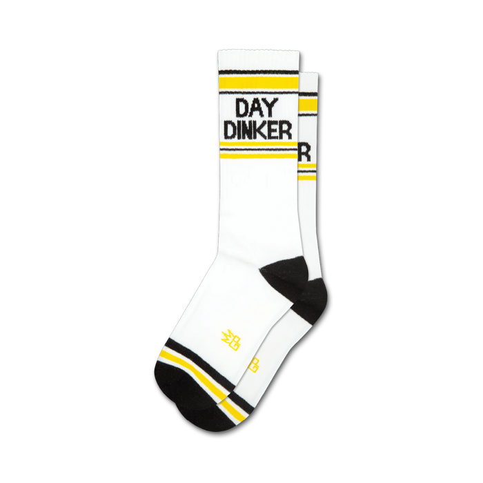 Pair of white crew socks with black and yellow stripes near the cuff. 'DAY DINKER' is written in black on the socks. }}