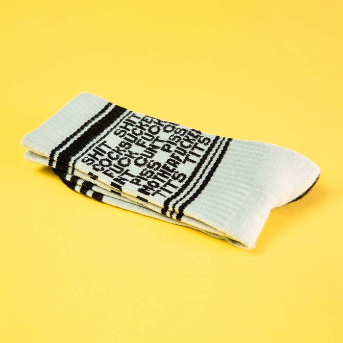 Close-up of a single 'Dirty Words' sock folded on a yellow background, highlighting the detail and texture.