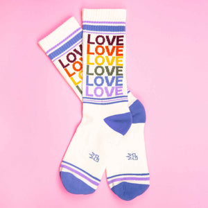 Pair of 'Love' rainbow socks on pink background.