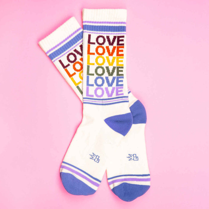 Pair of 'Love' rainbow socks on pink background.