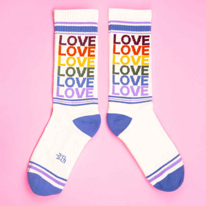 Flat lay of 'Love' rainbow socks on pink background.