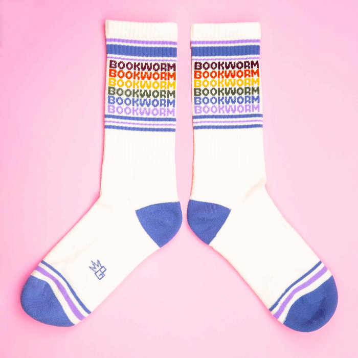 Flat lay product shot of two Bookworm socks on a pink background; socks are laid out in a more open position than in the previous image.