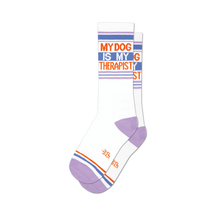Pair of white crew socks with lavender heel and toe. Blue, orange, and lavender stripes accent the white background with the text 'My Dog Is My Therapist'. }}
