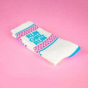 Close-up of folded 'Run Girl Run' socks on pink background. Highlights the sock's texture and design details.
