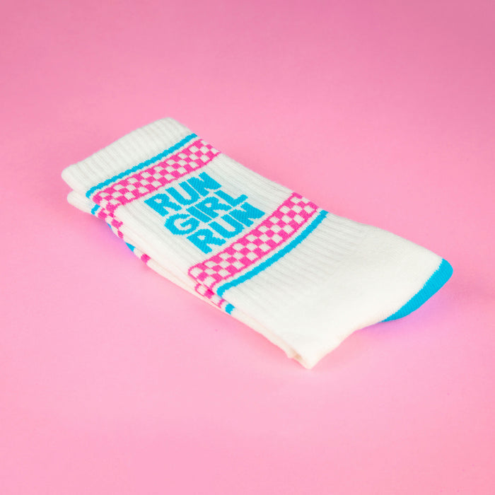 Close-up of folded 'Run Girl Run' socks on pink background. Highlights the sock's texture and design details.